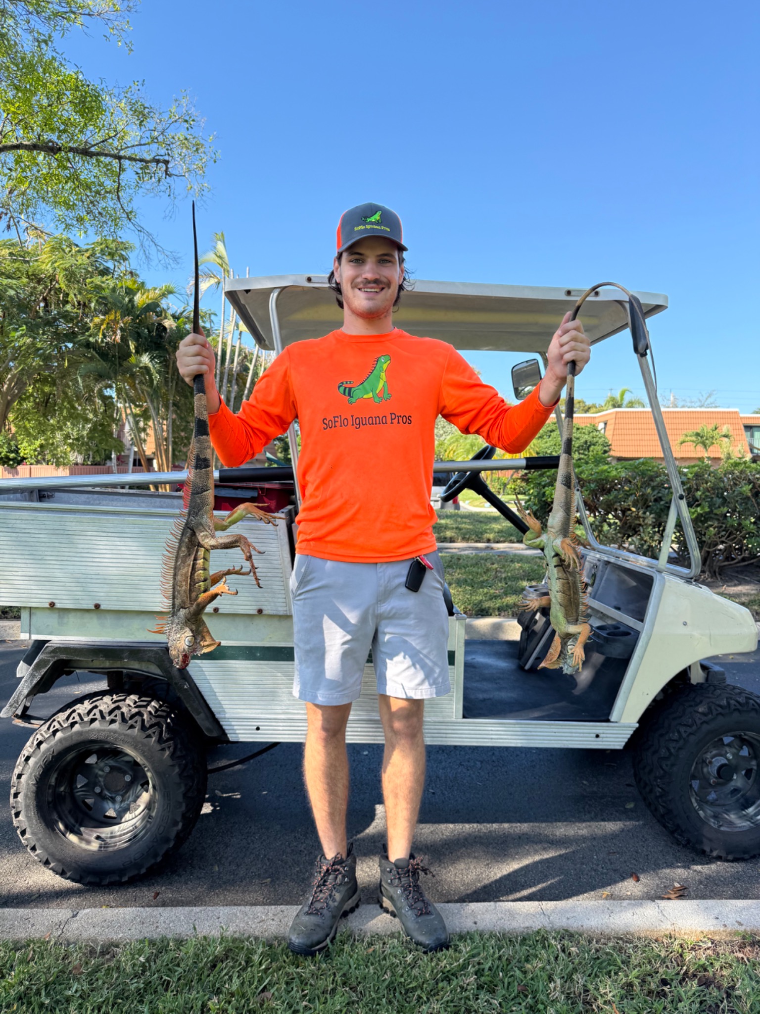 Iguana removal technician standing beside community utility cart